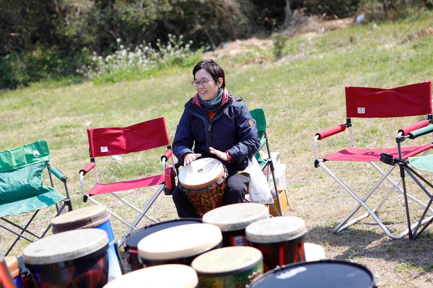 写真:キャンプ場でたくさんの太鼓に囲まれながら太鼓を叩く女性