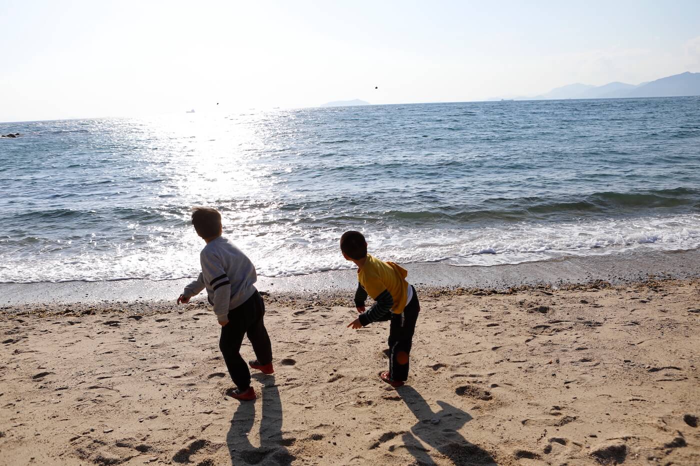 写真:海に向かって石を投げる子どもたち