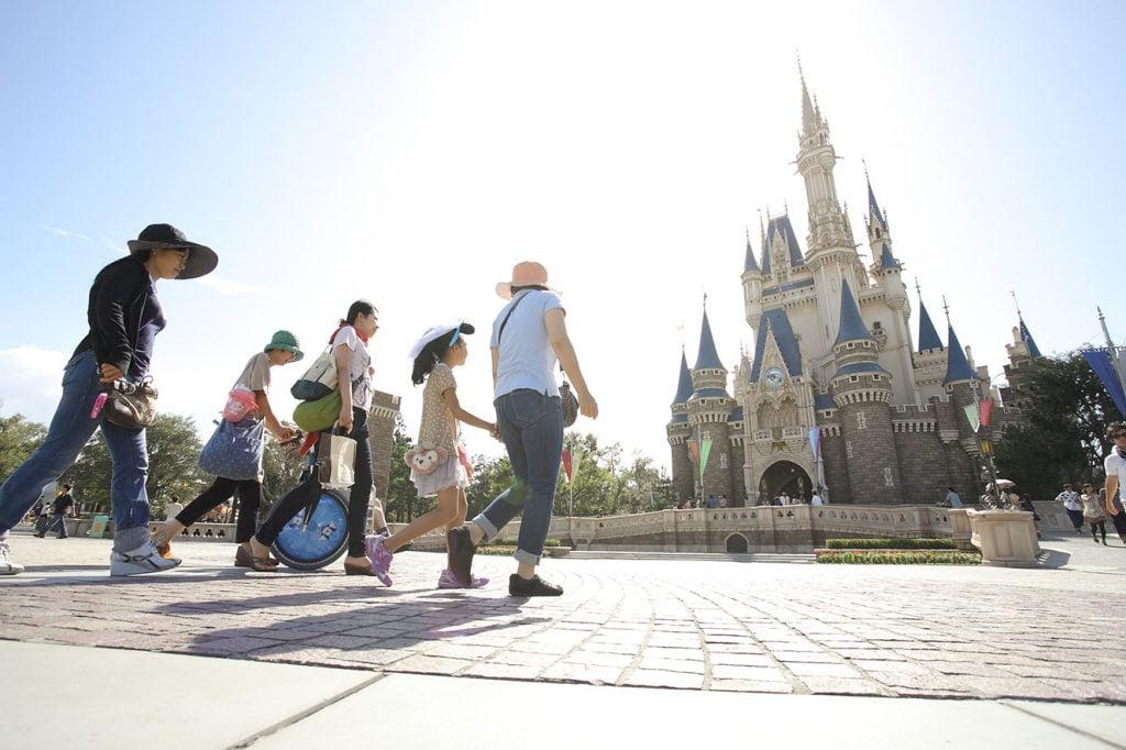 写真：車椅子を利用する子どもとその家族がテーマパークを訪れている様子