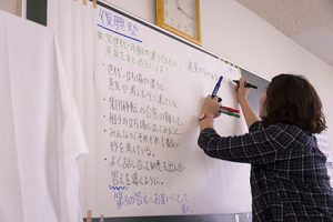 写真:支援活動のリストをホワイトボードに書く女性