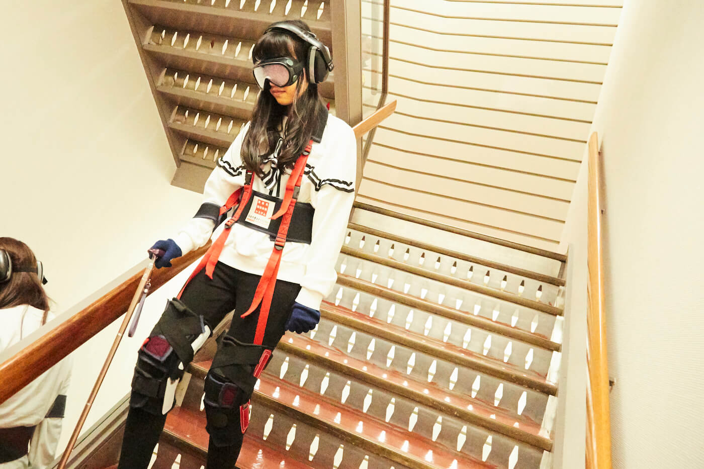 写真:高齢者体験キットを装着した状態で階段を降りる祝さん
