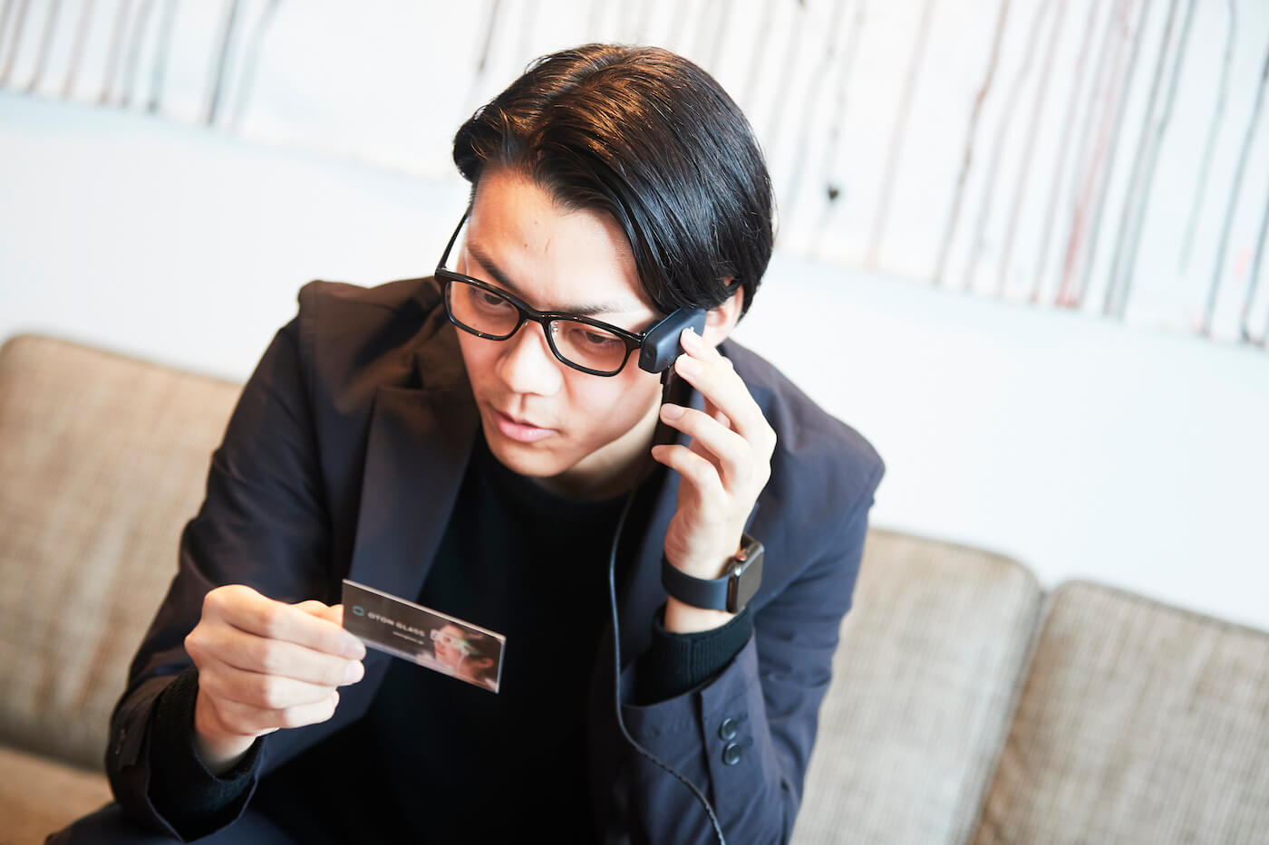 写真;OTON GLASSを装着し、名刺に書かれた文字を音声に変換する島影さん