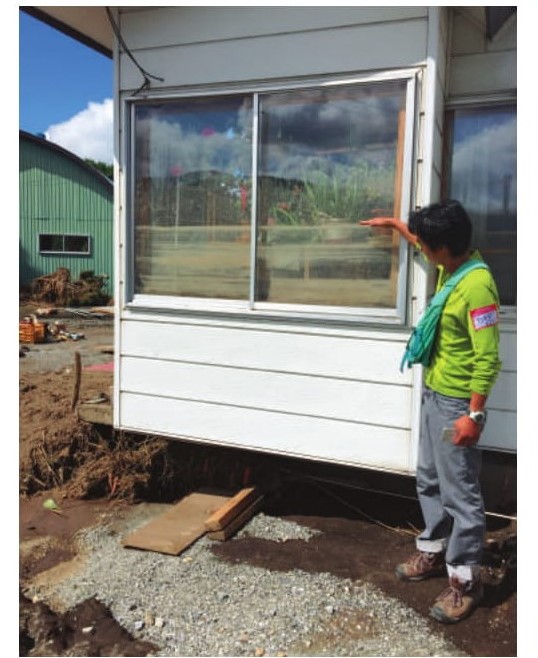 写真:家の前に立ち、浸水した高さを測る男性