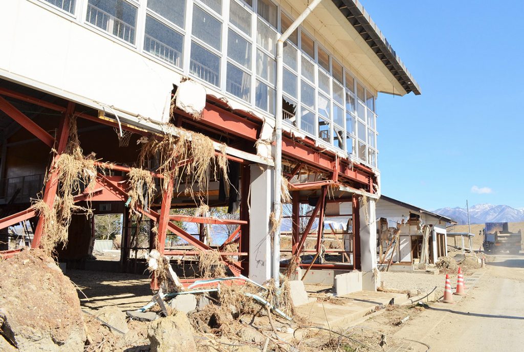 写真:白い壁に大きく穴が開き、柱がむき出しになっている長沼体育館