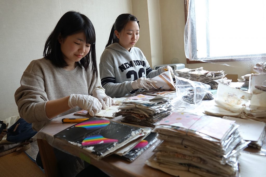 写真:テーブルの上に、水に浸かったアルバムを並べて、写真を切り出す立川さんたちの様子