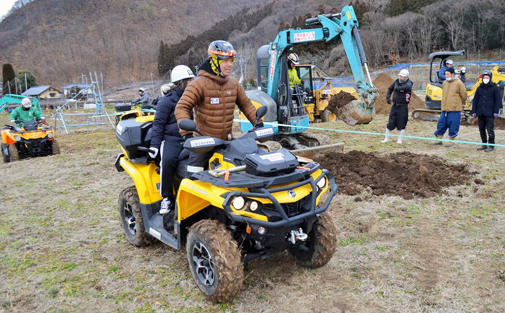 写真:黄色のバギーカーにまたがり、運転方法を参加者に教える林さん