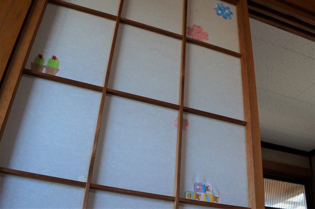 写真:破れた障子に学生ボランティアが貼った折り紙。サボテンや花の形の折り紙が貼られていました