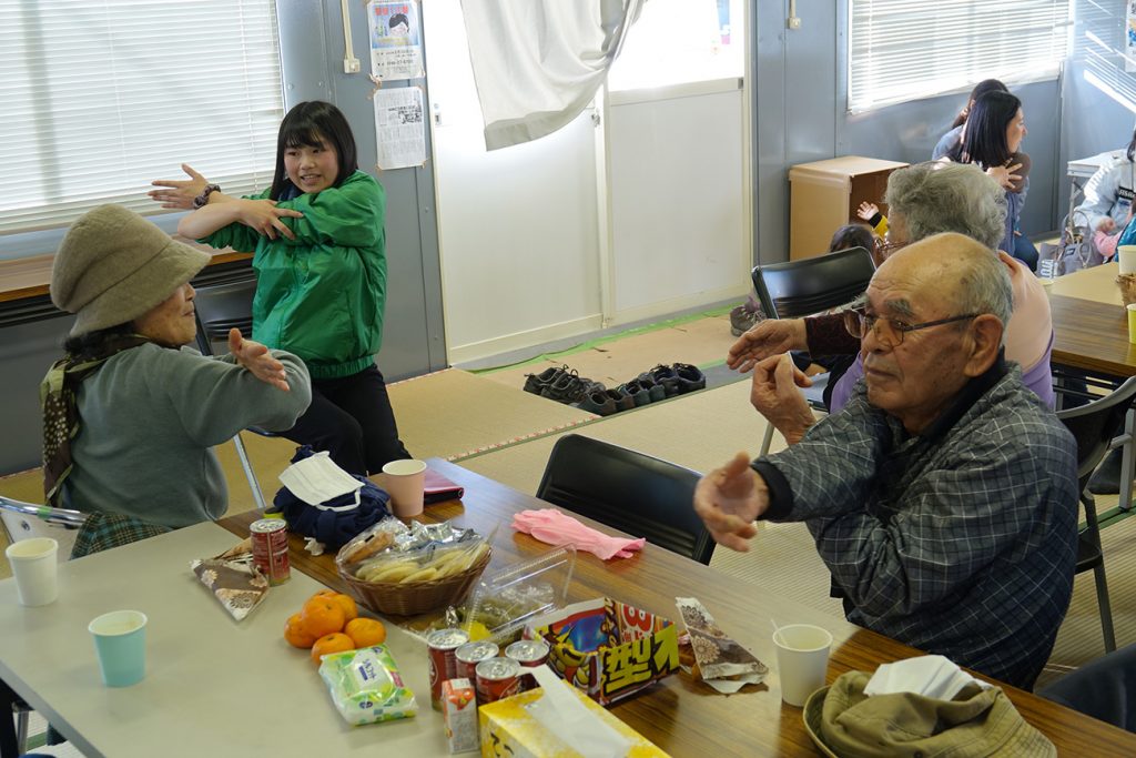 写真:プレハブ小屋にあつまった参加者たちがストレッチしている様子