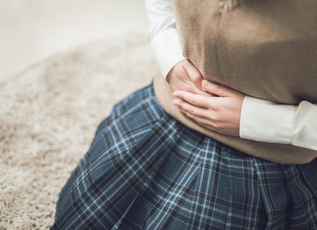 写真:妊娠したかもしれないとお腹を抱える女子高生