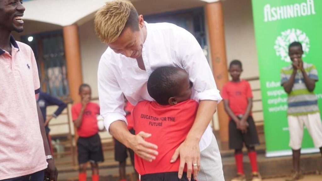 写真:抱きつくアフリカ人の子どもを優しく抱擁する本田圭佑さん