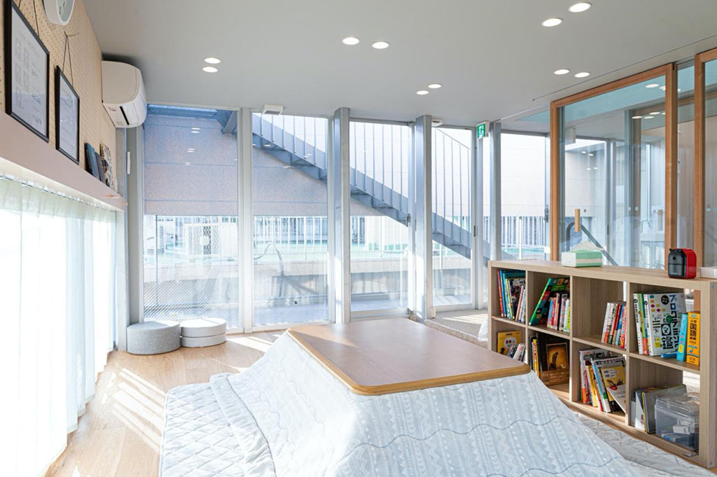 写真:中央にこたつテーブル。部屋の外側はガラス囲まれており室内がとても明るく感じる。