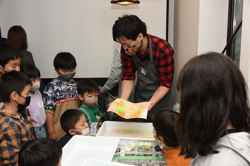 写真:マーブリングアートの作り方の説明を受ける子どもたちの様子