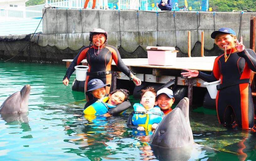 写真:沖縄県恩納村のレスパイト拠点、Hope& Wishバケーションハウスで、スタッフのサポートのもとイルカと遊ぶ難病の子どもたち