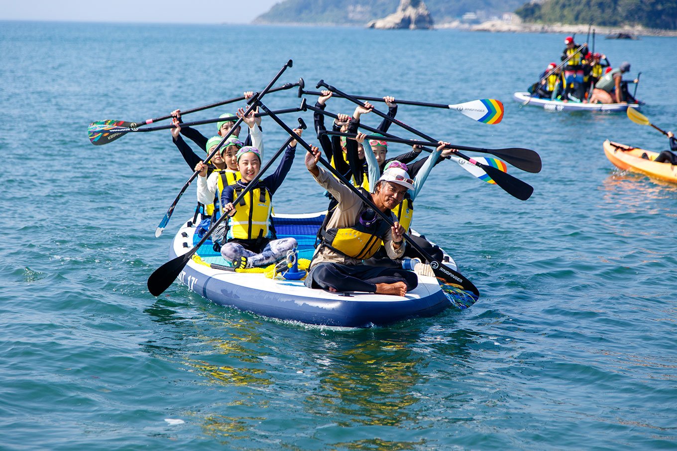 写真:海ごみ拾いイベントで回収された沢山のごみと、イベント参加者たちの集合写真。