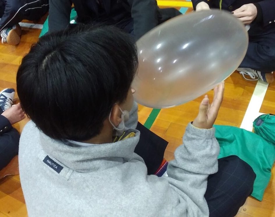 写真:コンドームに息を吹き込んで膨らませる生徒