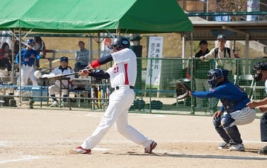 写真：ボールを打つバッター、かまえるキャッチー