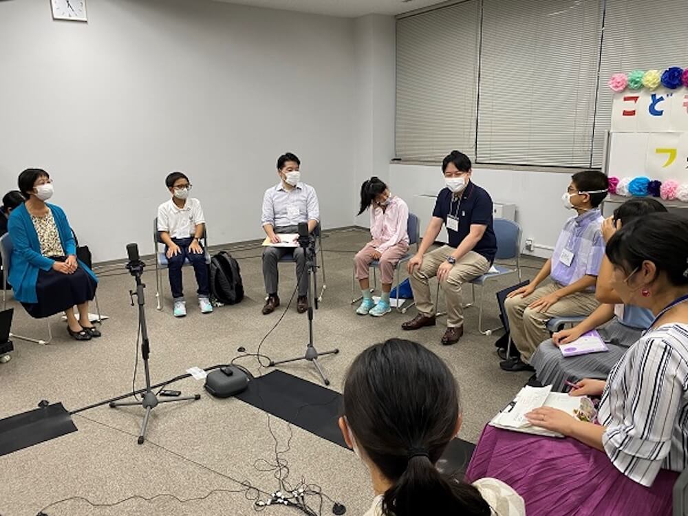 写真:複数の大人と子どもが円になって意見を交わす様子