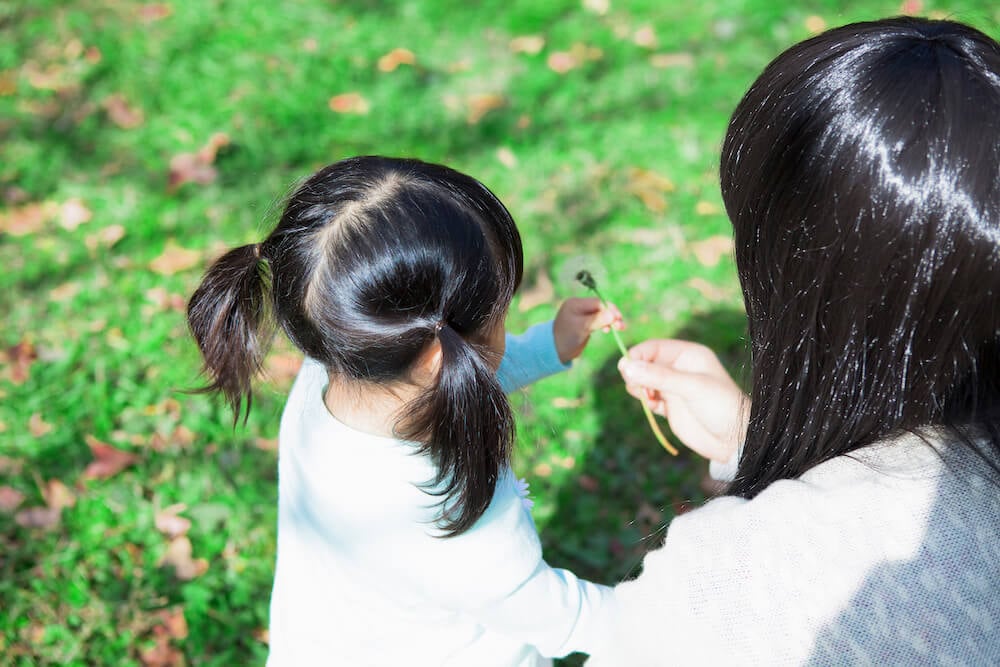 写真：公園で遊ぶ幼い子どもと母親