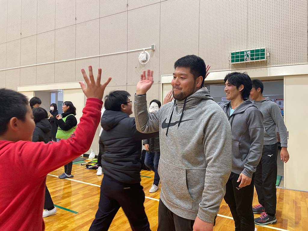 写真：子どもたちとハイタッチするHEROsアスリート