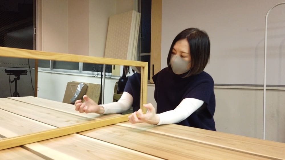 鏡に左腕を映し、鏡療法を行っている