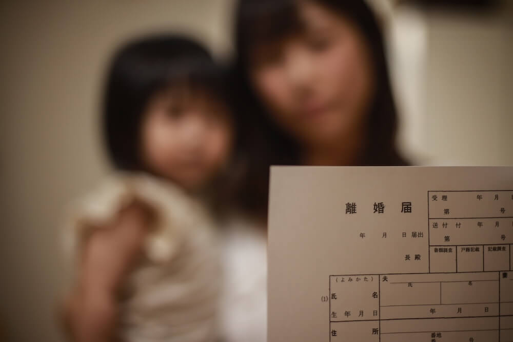 イメージ:離婚届を持つ、幼い子どもを抱えた女性