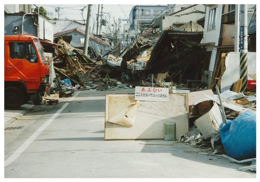 写真：阪神・淡路大震災での被災地の様子。道路を塞いでいる倒壊した家屋。
