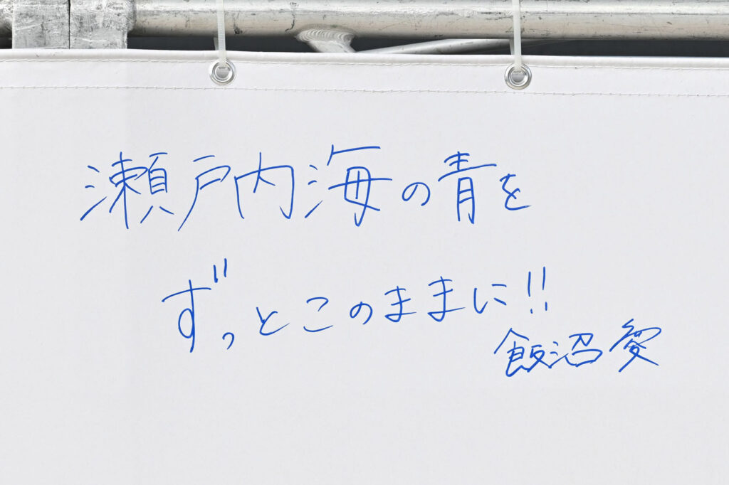写真：メッセージフラッグに書かれた飯沼さん自筆のメッセージ「瀬戸内海の青をずっとこのままに‼ 飯沼愛」
