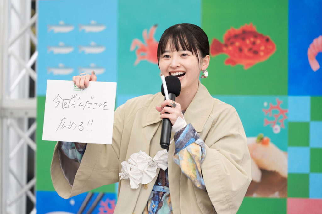 写真：直筆で「今日学んだことを広める‼」と書かれたボードを持つ飯沼さん