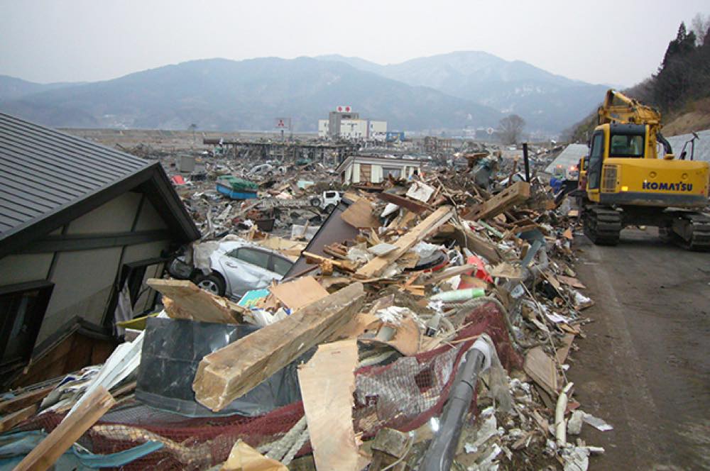 重機を使って道路をふさいでいたがれきを道路脇に積み上げている