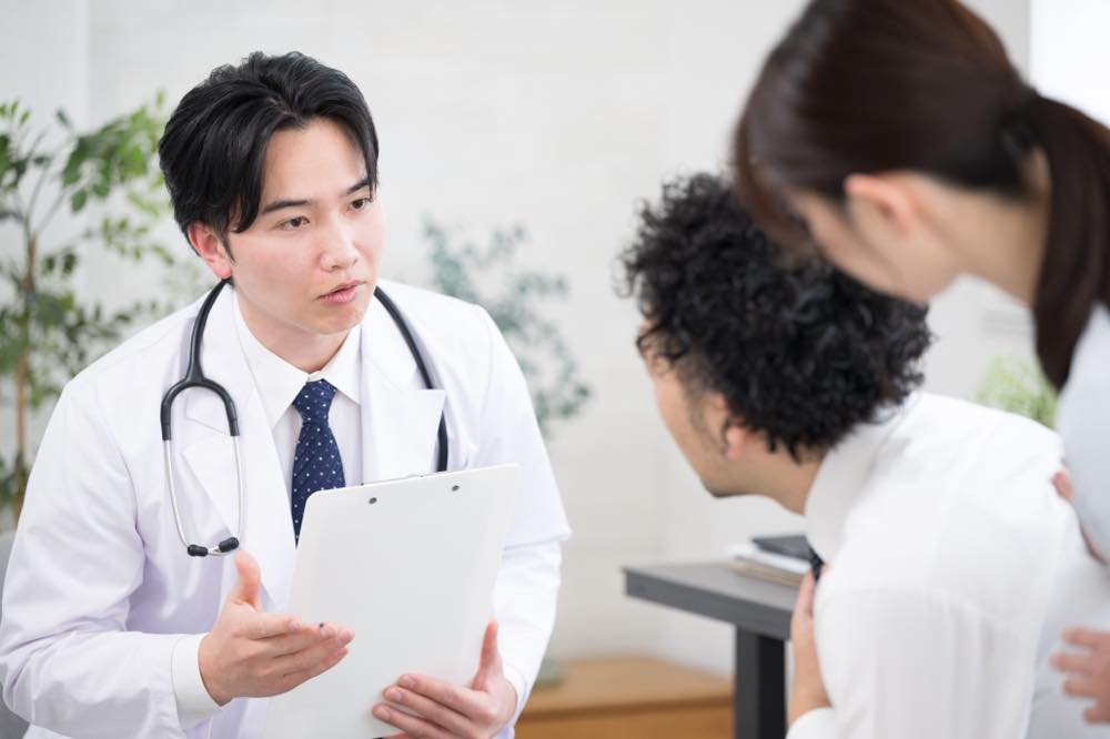 患者と見られる男性が女性と共に病院に訪れており、男性の医師と話している