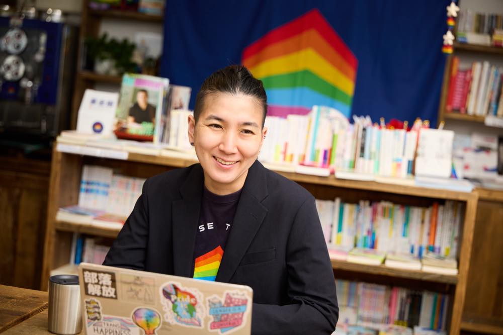 インタビューに答える小野さん。目の前のパソコンには、さまざまなステッカーが貼られている。