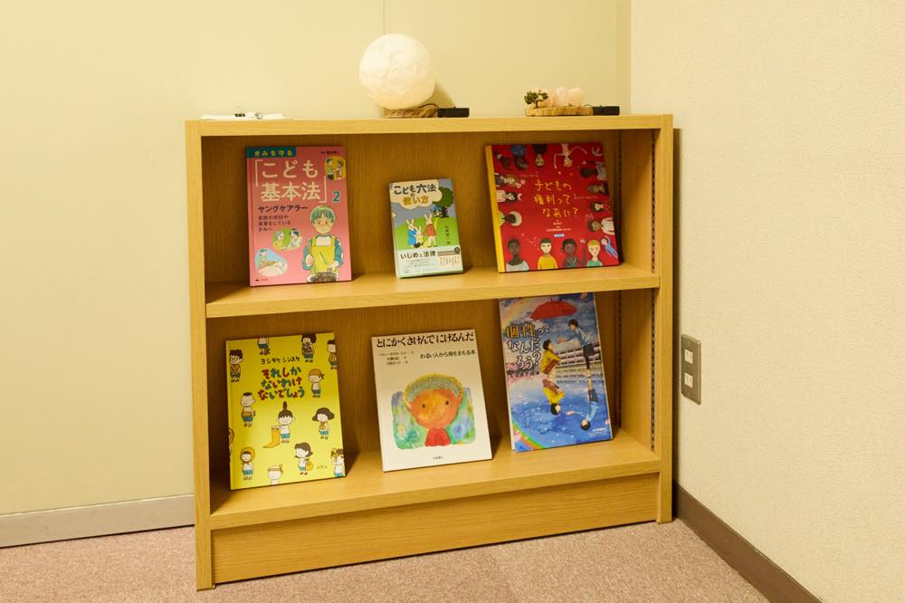 面談室の本棚。以下の本が置かれている。

② ヤングケアラー　家族の世話や家事をしているきみへ 

こども六法の使い方

子どもの権利ってなあに? 

それしかないわけないでしょう

とにかくさけんでにげるんだ

個「性」ってなんだろう？：LGBTの本
