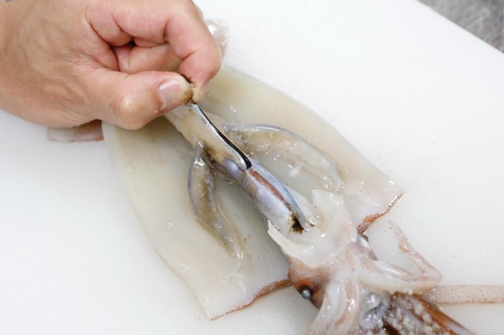 指でイカの墨袋を引っ張っている様子