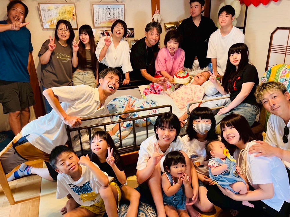 病院のベッドを囲んで集まった大勢の人々の写真