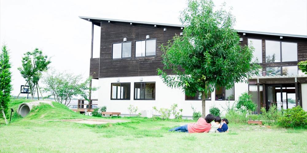 2010年4月に福岡市西区今津に開村した「子どもの村福岡」の外観。茶色と白の建物が広々とした芝生の庭に建っている