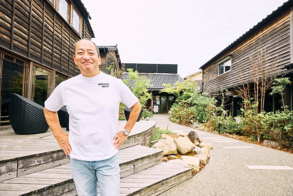 輪島カブーレの前に立ち笑顔を向ける雄谷さん