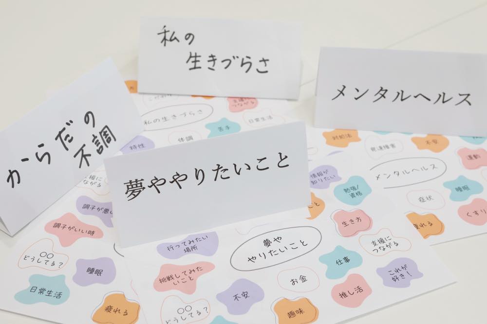 「女子会」でテーブルに置かれるテーマカードの写真。からだの不調、私の生きづらさ、夢ややりたいこと、メンタルヘルス、という言葉が書かれたカードが並んでいる