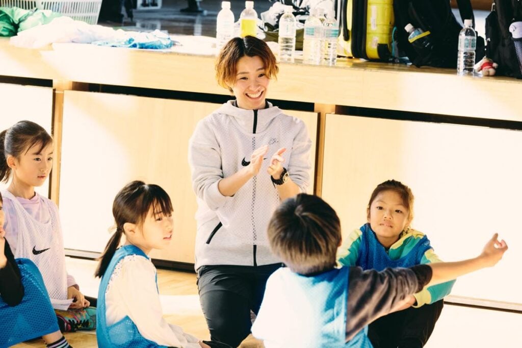 小学校の体育館で、子どもたちに囲まれながら指導を行う井上さん