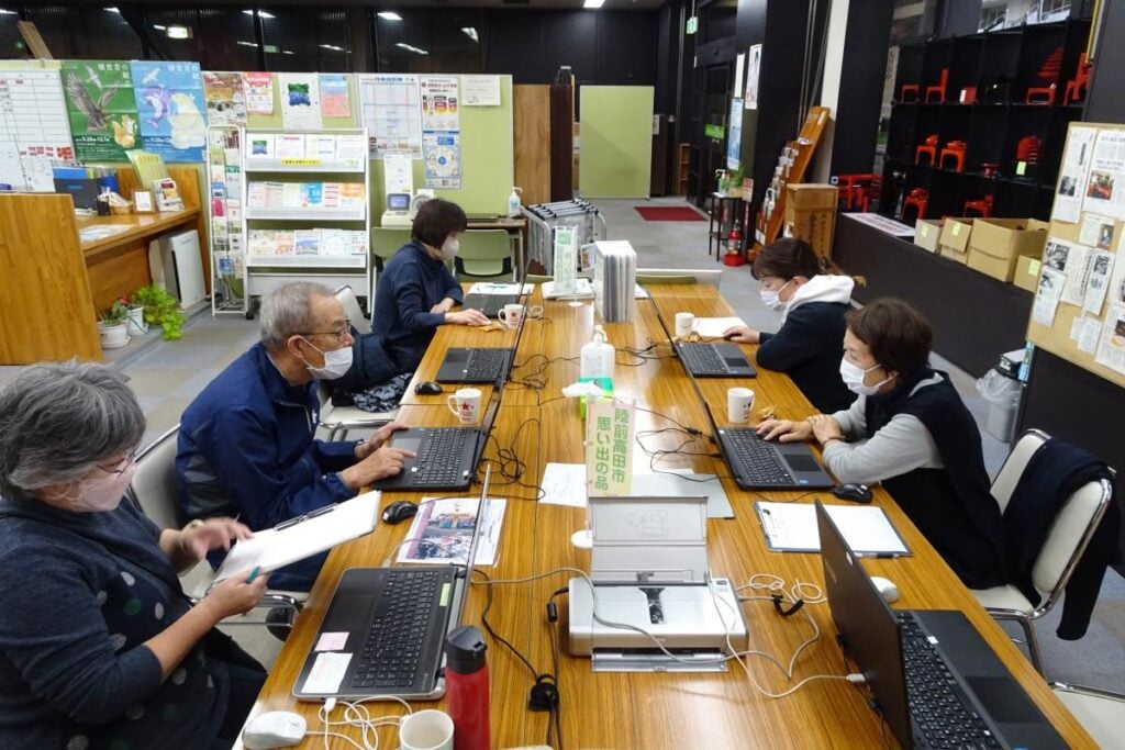 2024年11月に盛岡で開催された「思い出の品」返却会の様子。長テーブルに並んだ複数のノートパソコンを使用して参加者がデータ確認を行っている