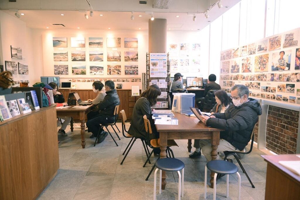 2019年3月に東京・原宿で行われた出張返却会の様子。壁一面に写真が展示され、来場者がファイルを閲覧している