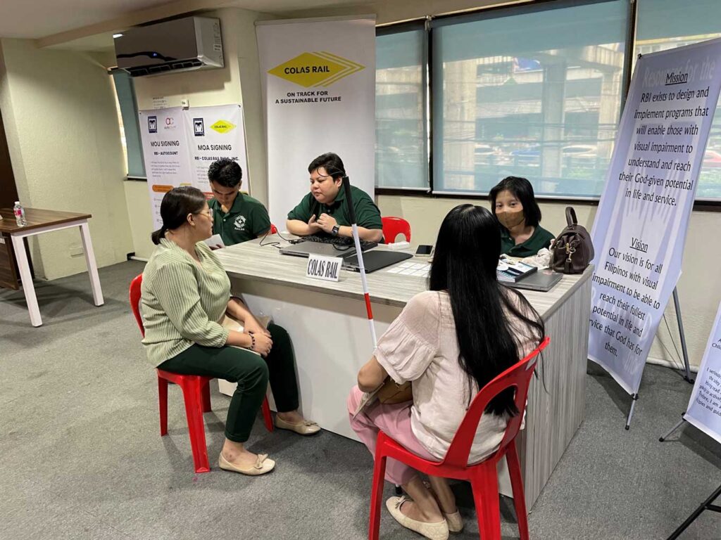 写真:企業ブースで視覚障害のある参加者と担当者が向かい合い、就職のための面接を行っている様子。